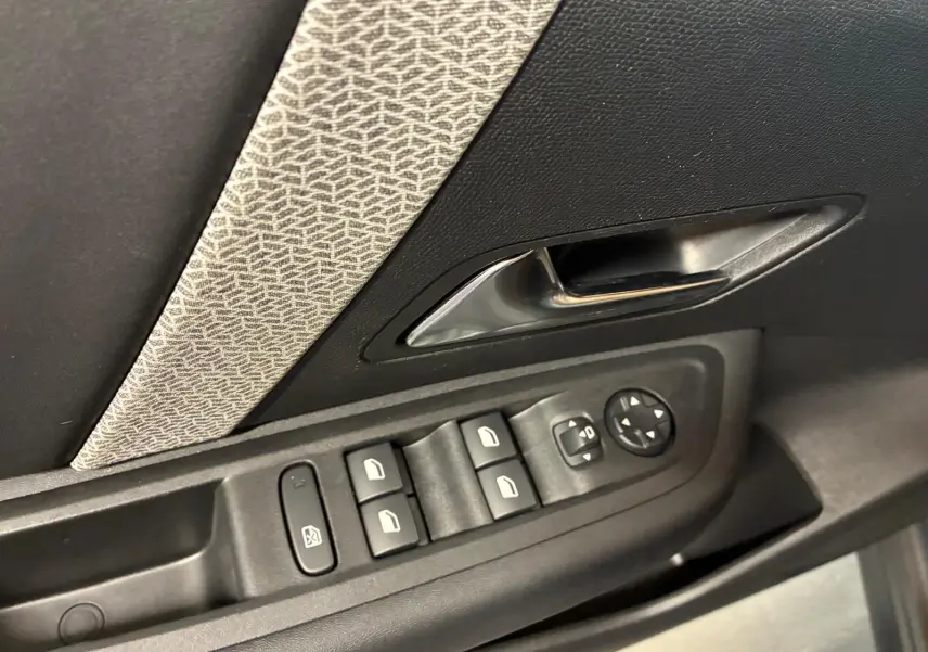 Gros plan sur la commande des vitres et la poignée intérieure côté gauche d’une Citroën C4 X gris, tissu gris-noir.