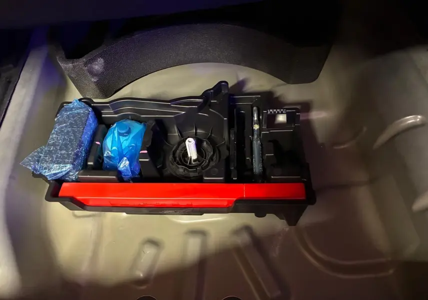 Rangement d’outils dans le coffre d’une Citroën C4 X gris, vue plongeante sur les accessoires bien rangés.