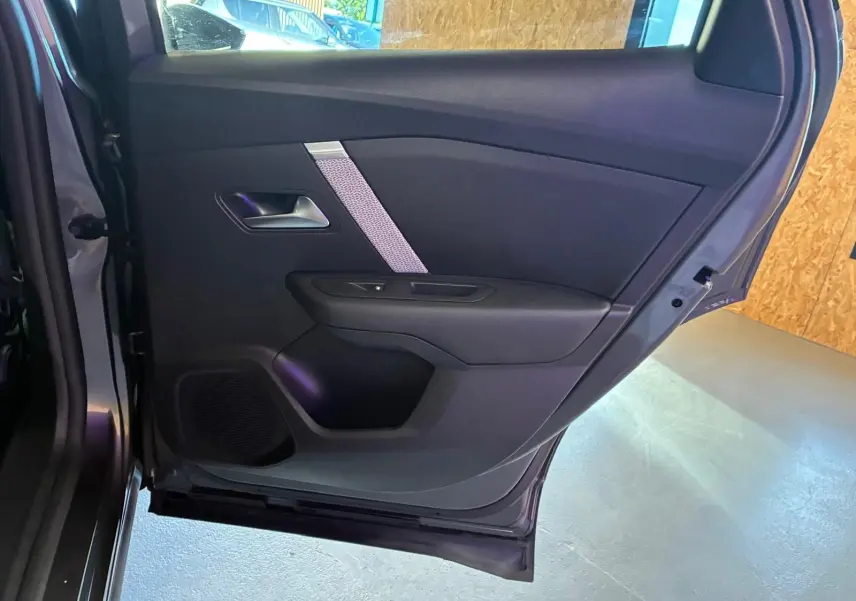 Vue intérieure de la porte arrière gauche d'une Citroën C4 X gris, avec garniture noire et insert décoratif argenté.