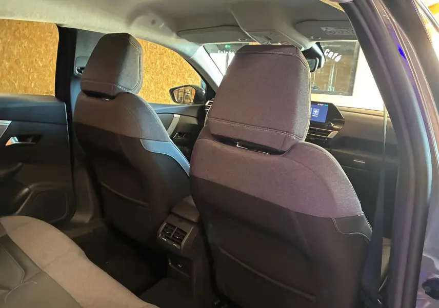 Vue intérieure arrière du Citroën C4 X gris 2024, montrant les sièges avant en tissu gris et la console centrale avec aérateurs.