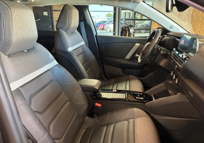 Vue intérieure côté conducteur de la Citroën C4 X 1.5 BlueHDi 130 gris, sièges tissu et cuir bicolore, tableau de bord moderne.