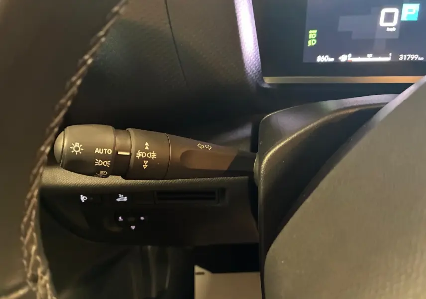 Gros plan sur la commande des feux à gauche du volant du tableau de bord d'une Citroën C4 X gris 2024.