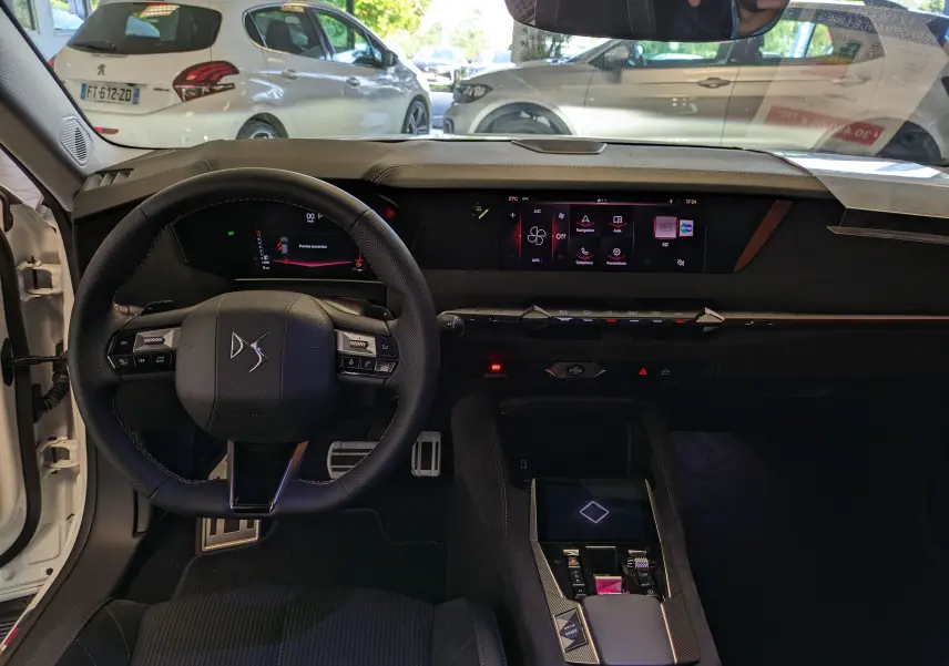 Vue intérieure du poste de conduite du DS4 blanc nacré 2024, avec volant compact, écran tactile central et finitions Alcantara® élégantes.