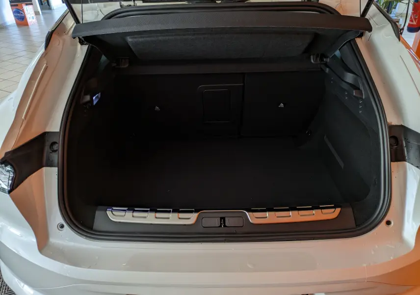 Coffre ouvert vu de l'arrière d'une DS4 blanche nacrée 2024, montrant l'espace de chargement vide et le seuil de coffre.