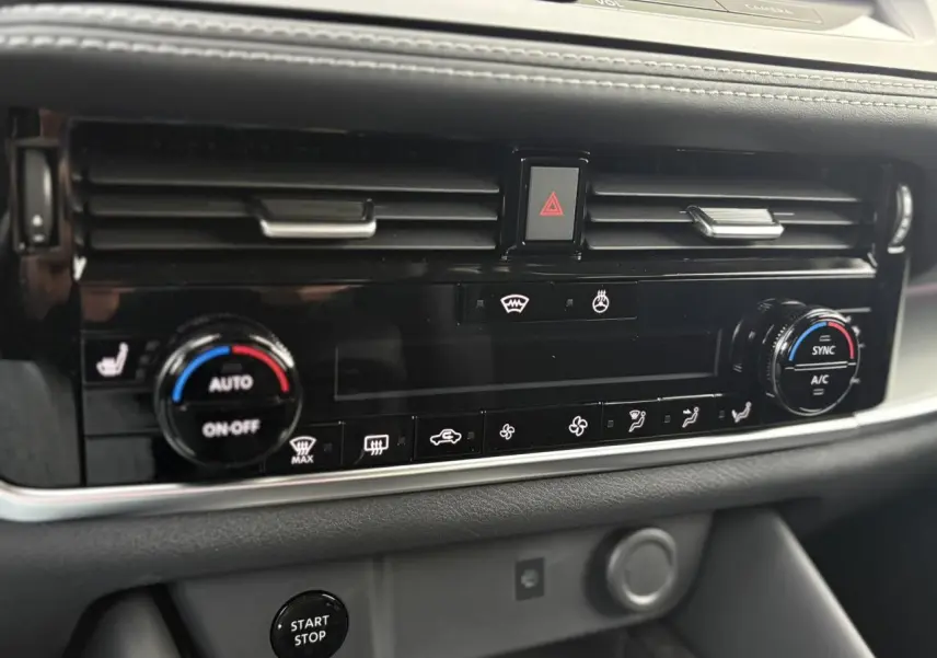 Vue rapprochée de la console centrale noire du Nissan Qashqai 2025, montrant les commandes de climatisation et le bouton Start/Stop.