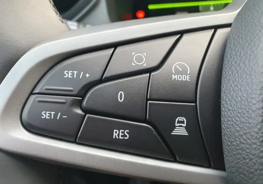 Gros plan sur les commandes du régulateur de vitesse au volant du Dacia Bigster, finition noire et gris argenté.