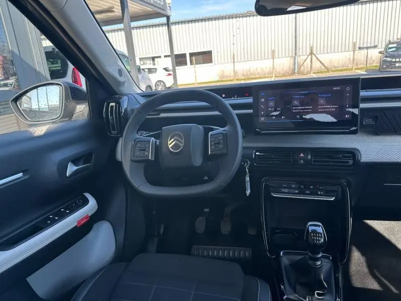 Vue intérieure de face du poste de conduite du Citroën C3 1.2 Turbo 100ch MAX 2025 noir avec volant multifonction et boîte manuelle.