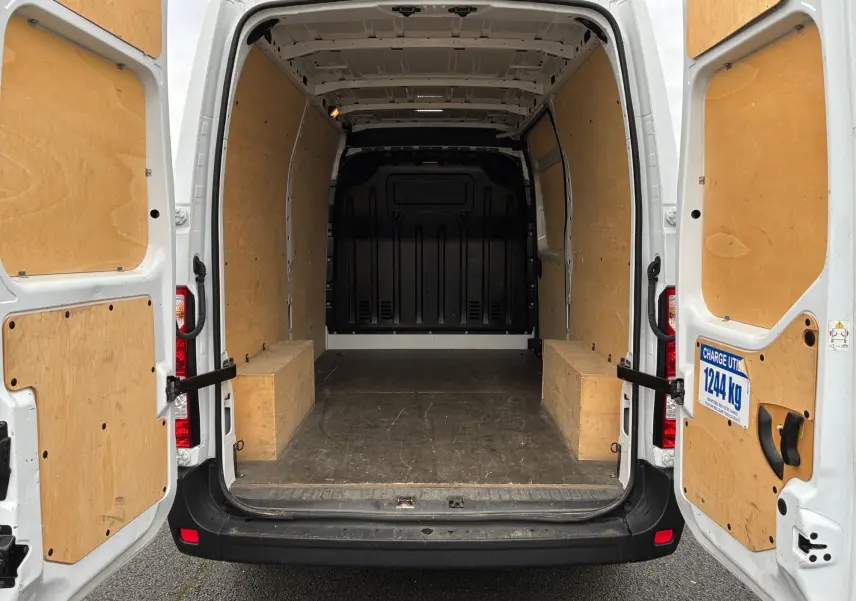 Vue arrière ouverte du Renault Master blanc 2024, montrant l'intérieur utilitaire avec parois et plancher en bois.