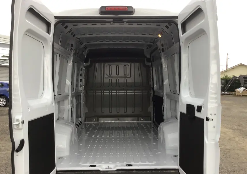 Vue arrière du Peugeot Boxer Fourgon blanc 2025 avec portes ouvertes montrant l'espace de chargement vide et la structure métallique intérieure.
