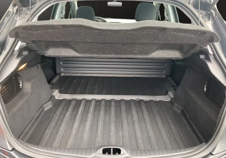 Coffre ouvert d'une Peugeot 208 Affaire noir, vue arrière montrant l'espace de chargement avec tapis en caoutchouc.