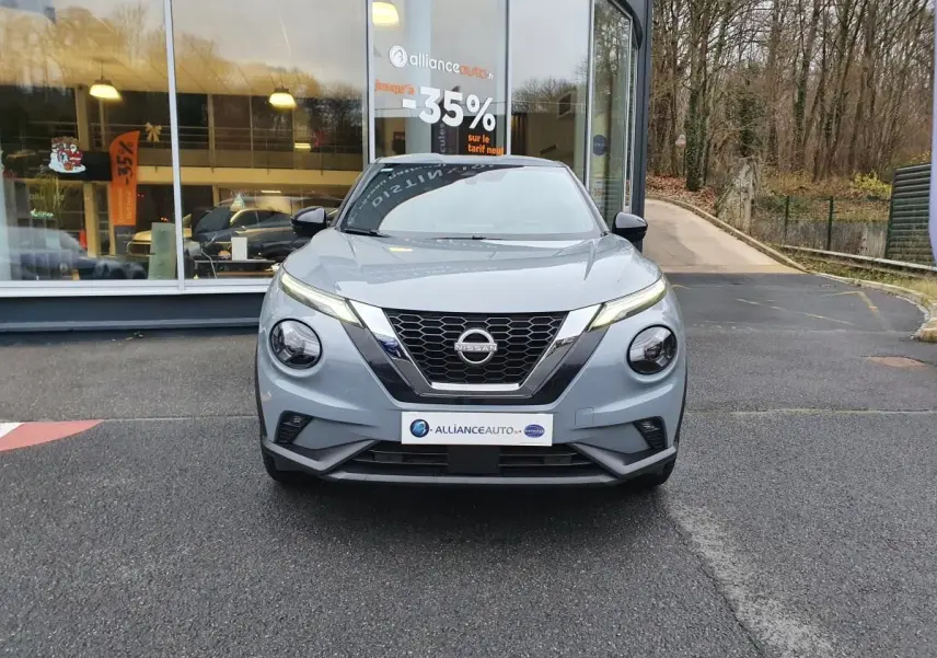 Nissan Juke gris céramique vue de face, mettant en valeur sa calandre en V et ses phares ronds distinctifs.