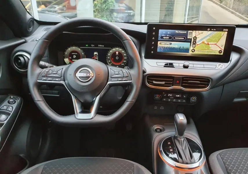 Vue intérieure avant du Nissan Juke 2025 avec volant multifonction, écran tactile 12,3 pouces et levier de boîte automatique.