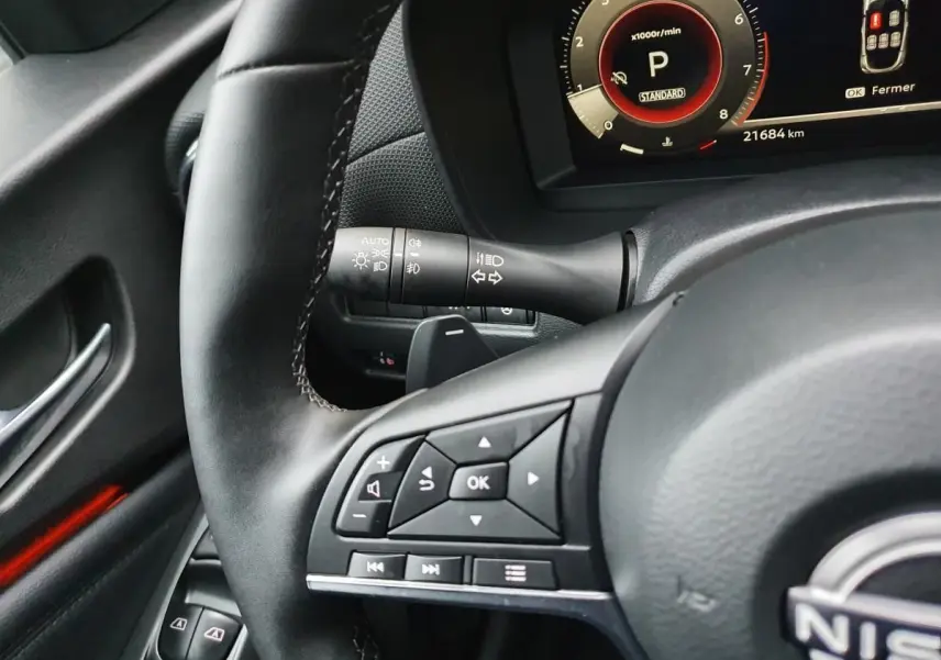 Gros plan sur le volant noir du Nissan Juke 2025 avec commandes multifonctions et compteur digital en arrière-plan.