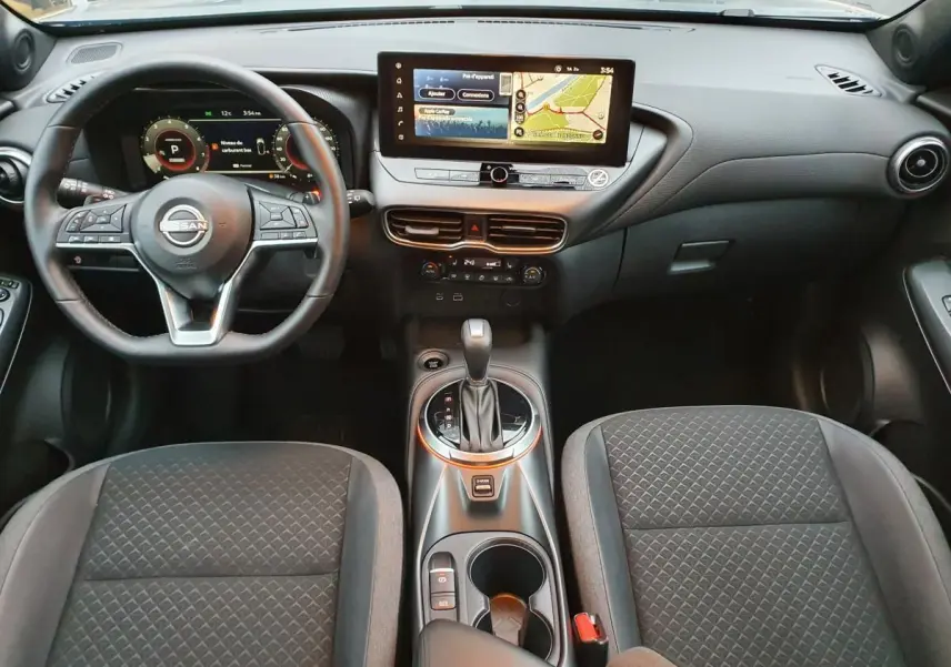 Intérieur du Nissan Juke 2025 avec tableau de bord moderne, écran tactile 12,3 pouces et console centrale avec boîte auto.