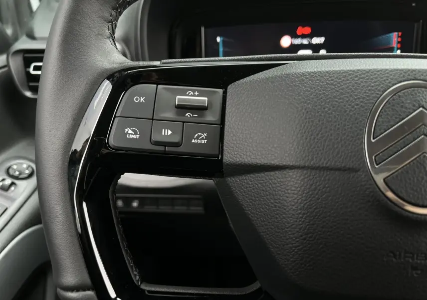 Gros plan sur le volant cuir du Citroën Berlingo Multispace blanc, avec commandes multifonctions visibles à gauche.