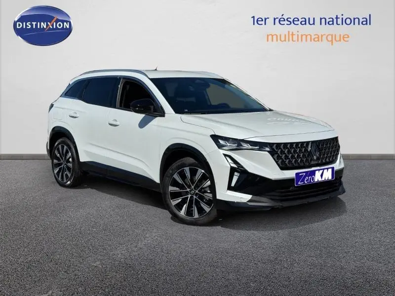 Vue 3/4 avant d'un SUV blanc avec jantes alliage noires et toit contrasté, stationné sur sol gris.