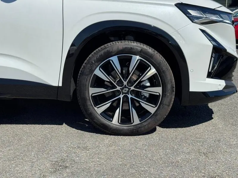 Gros plan sur la roue avant droite et partie avant blanche du Renault Austral 2025 avec jante alu bicolore design moderne.