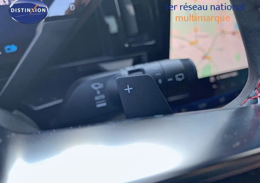 Gros plan sur la palette de changement de vitesses "+" du volant d'un Renault Austral blanc métal au toit noir, intérieur moderne.