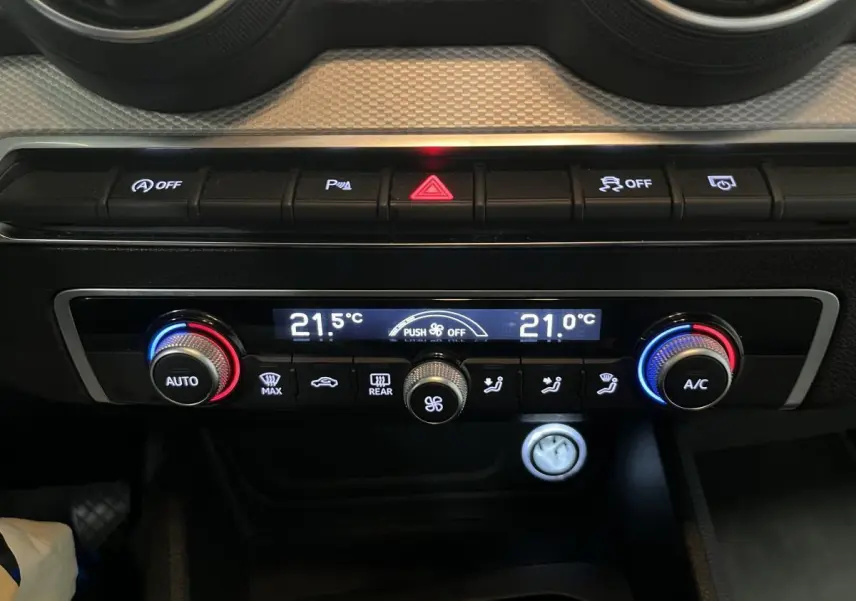 Détail de la console centrale de l'Audi Q2 gris, avec commandes de climatisation automatique et boutons fonctionnels.