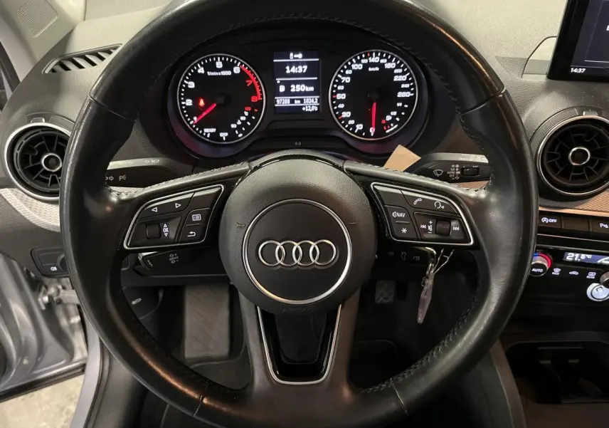 Vue intérieure centrée sur le volant cuir multifonction et la console centrale d'une Audi Q2 Business line gris 2019.