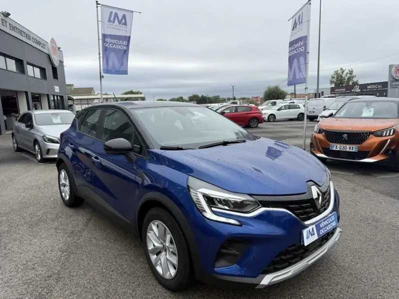 Renault Captur E-Tech 145 Zen bleu métal vu en 3/4 avant droit sur parking de véhicules d'occasion.