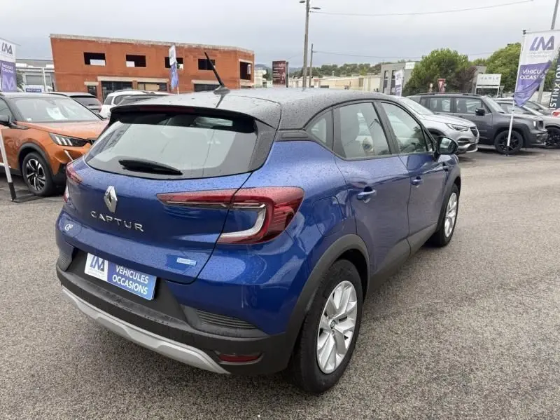 Vue 3/4 arrière droite d'un Renault Captur E-Tech 145 Zen bleu métal 2022 avec toit noir et feux LED distinctifs.
