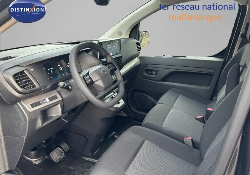 Vue intérieure côté conducteur du Citroën Jumpy Fourgon gris titane, montrant le tableau de bord et les sièges noirs.