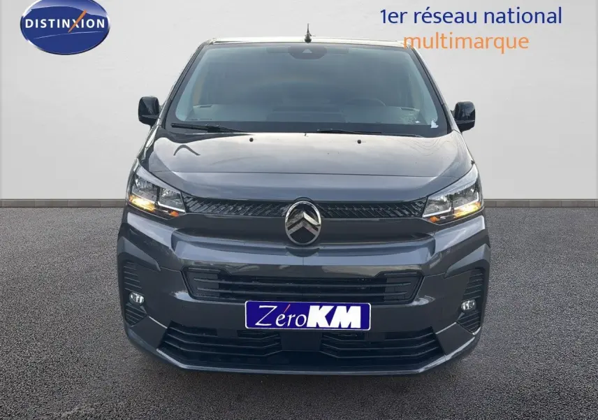 Vue frontale d'un Citroën Jumpy Fourgon XL gris titane métal avec feux allumés sur fond neutre.