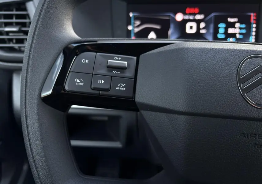 Gros plan sur le volant noir du Citroën Jumpy 2025, montrant les commandes de régulateur et l'affichage numérique flou.
