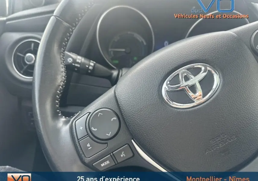 Gros plan sur le volant multifonctions noir de la Toyota Auris Business Hybride 2016 avec commandes audio intégrées.