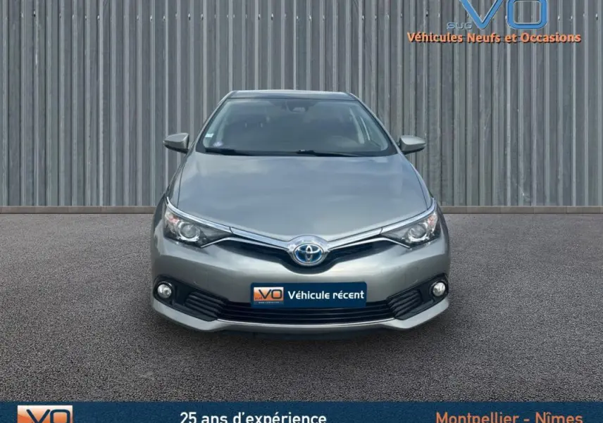 Vue avant d'une Toyota Auris Business Hybride 136h gris clair avec phares antibrouillard et calandre chromée.