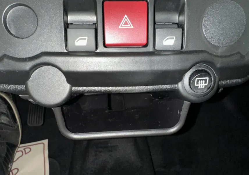 Gros plan sur les commandes centrales du tableau de bord de l'AIXAM AMBITION E CITY PACK rouge, avec bouton de warning rouge et commandes de vitres.