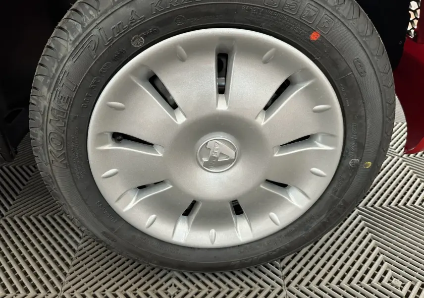 Gros plan sur la roue avant droite d'une Aixam Ambition E City Pack rouge avec enjoliveur argenté et pneu Komemet Plus.