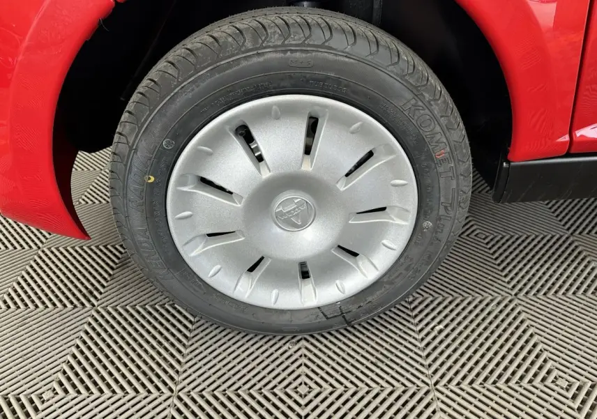 Gros plan sur la roue avant gauche d'une Aixam Ambition E City Pack rouge 2025 avec enjoliveur argenté.