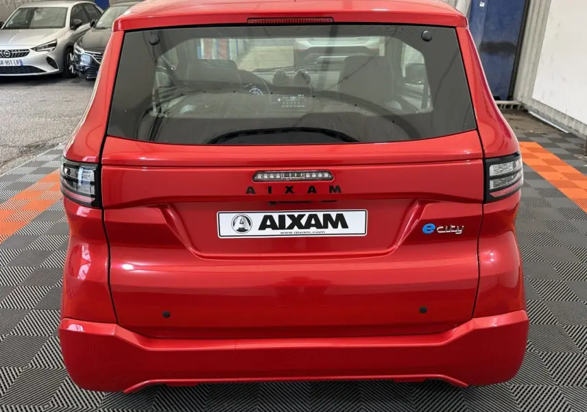 Vue arrière d'une AIXAM AMBITION E CITY PACK rouge électrique 2025 avec logo e-city et feux LED distinctifs.