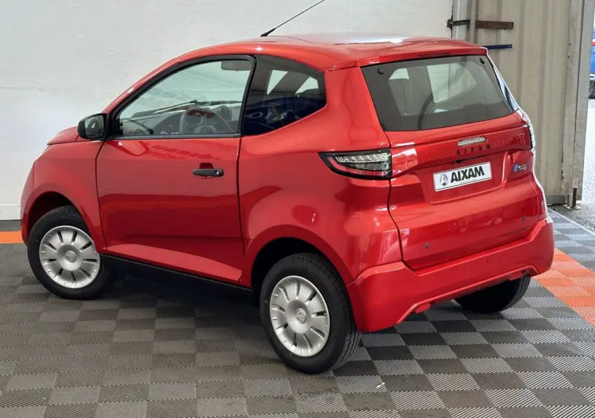 Vue 3/4 arrière droite d'une AIXAM Ambition E City Pack rouge 2025 avec rétroviseur caméra côté conducteur.