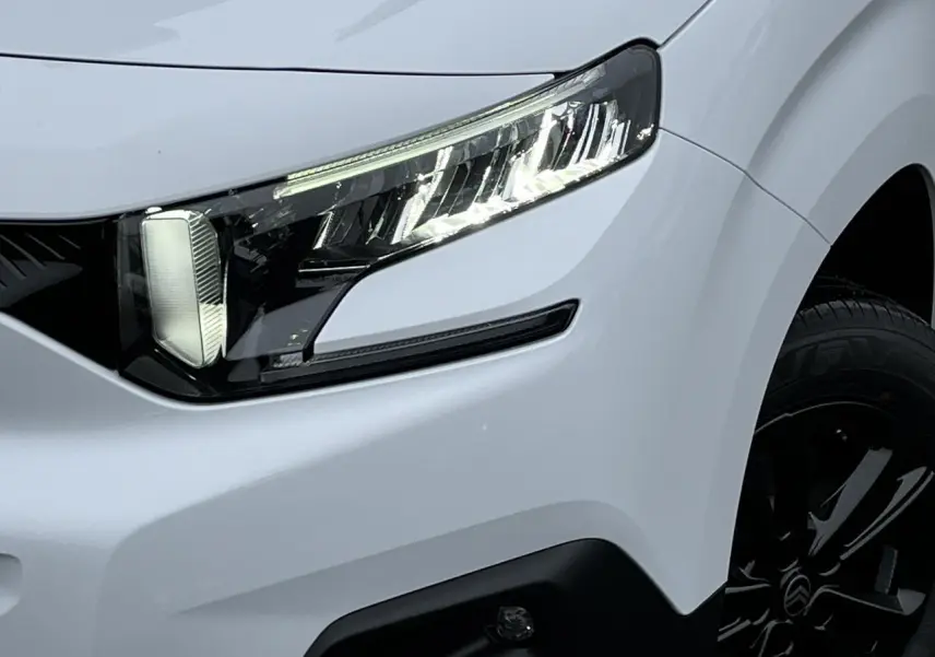 Gros plan sur l'avant droit du Citroën Berlingo blanc Glacier, avec phare LED et jante alliage noire visible.