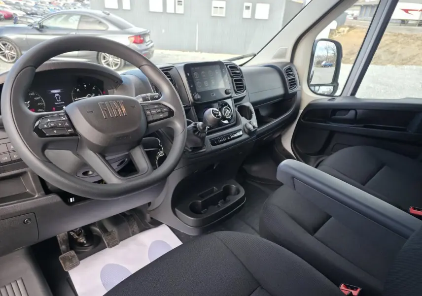Vue intérieure côté conducteur du Fiat Ducato Fourgon 2025, tableau de bord noir avec écran tactile 7 pouces et volant multifonction.