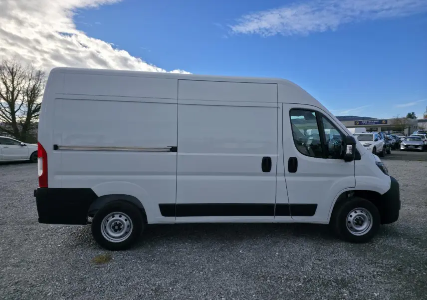 Vue de profil côté gauche d'un FIAT Ducato Fourgon blanc avec porte latérale coulissante et roues acier 15 pouces.