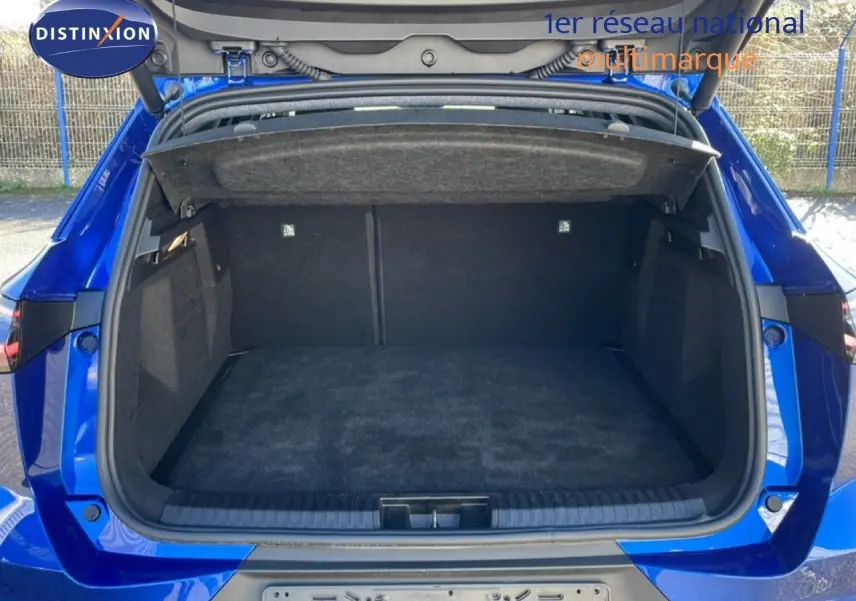 Coffre ouvert vu de l'arrière d'une Renault SYMBIOZ 1.6 E-TECH bleu iron metal, montrant un espace de chargement spacieux.