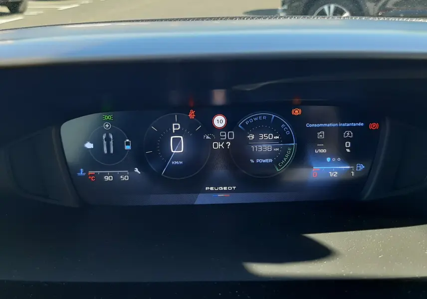 Tableau de bord numérique de Peugeot 308 SW Hybrid 2025, affichage central avec vitesse, autonomie et consommation instantanée.