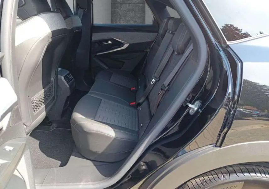 Vue côté gauche arrière du Peugeot 3008 New Hybrid 145 GT 360 noir perla nera, montrant la banquette arrière en tissu et cuir.
