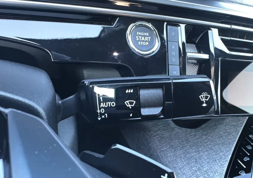 Gros plan sur la commande d’essuie-glace et bouton start/stop du tableau de bord du Peugeot 3008 hybride noir perla nera 2025.