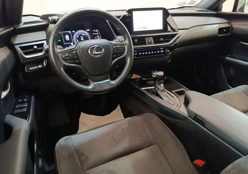 Intérieur du Lexus UX 250H 2WD gris clair, vue de face sur le volant, tableau de bord et écran tactile central.