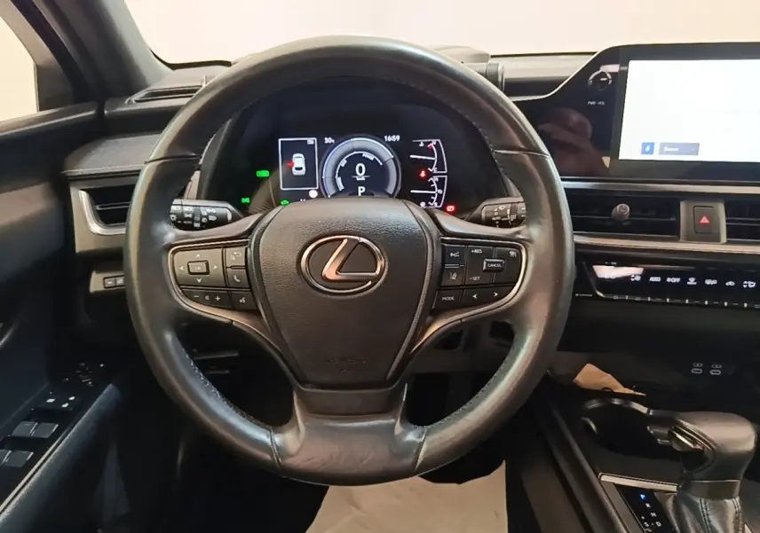 Vue centrée sur le volant cuir noir du Lexus UX 250H 2WD Pack Business avec tableau de bord digital et écran tactile.