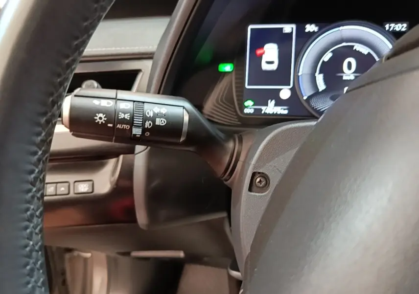 Gros plan sur le commodo gauche et le tableau de bord numérique du Lexus UX 250H gris clair, affichage multifonctions allumé.