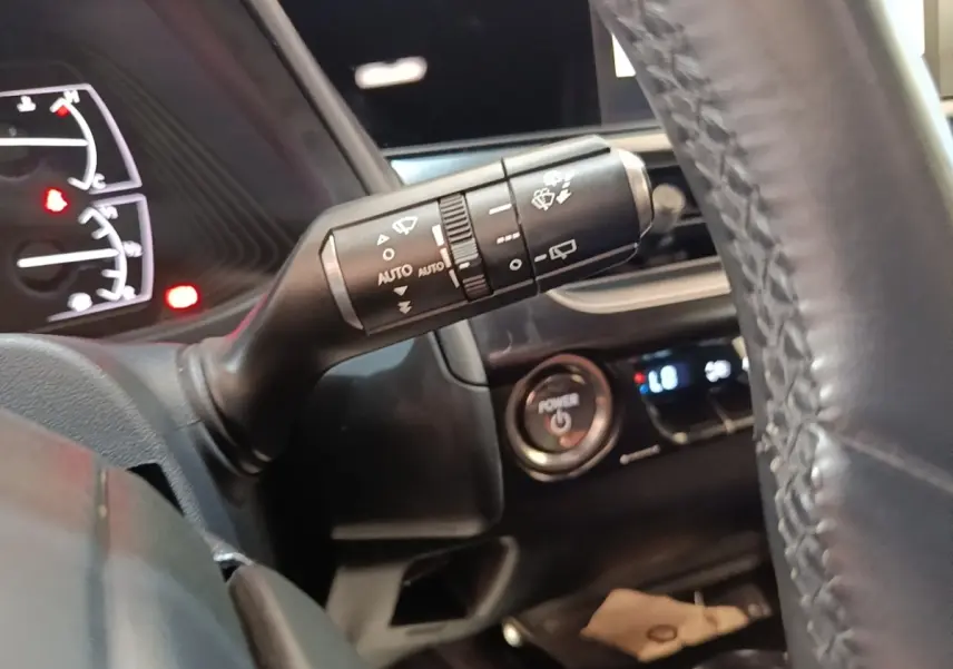 Gros plan sur la commande d’essuie-glace à gauche du volant cuir dans l’habitacle noir du Lexus UX 250H gris clair.
