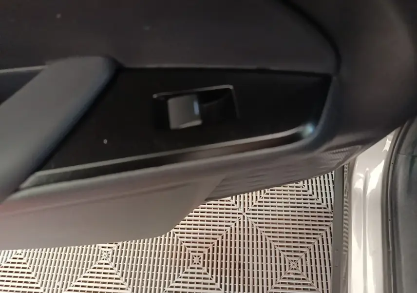 Détail intérieur montrant la poignée de porte côté droit du Lexus UX 250H gris clair, avec partie de la carrosserie visible.