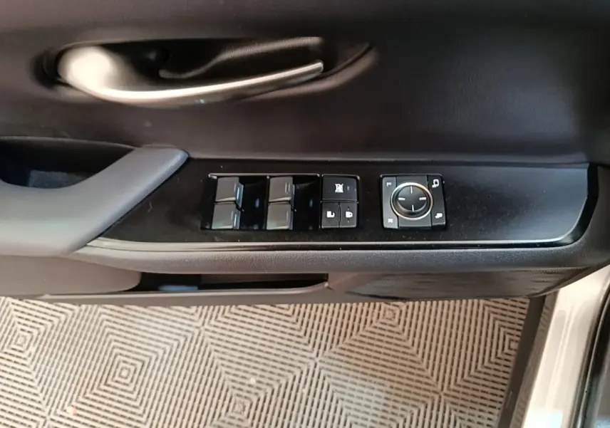 Vue rapprochée de la porte côté conducteur d’un Lexus UX 250H gris clair, avec commandes des vitres et rétroviseurs.