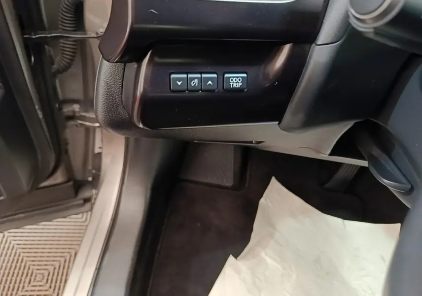 Vue intérieure côté conducteur du Lexus UX 250H gris clair, montrant les boutons de réglage du tableau de bord.
